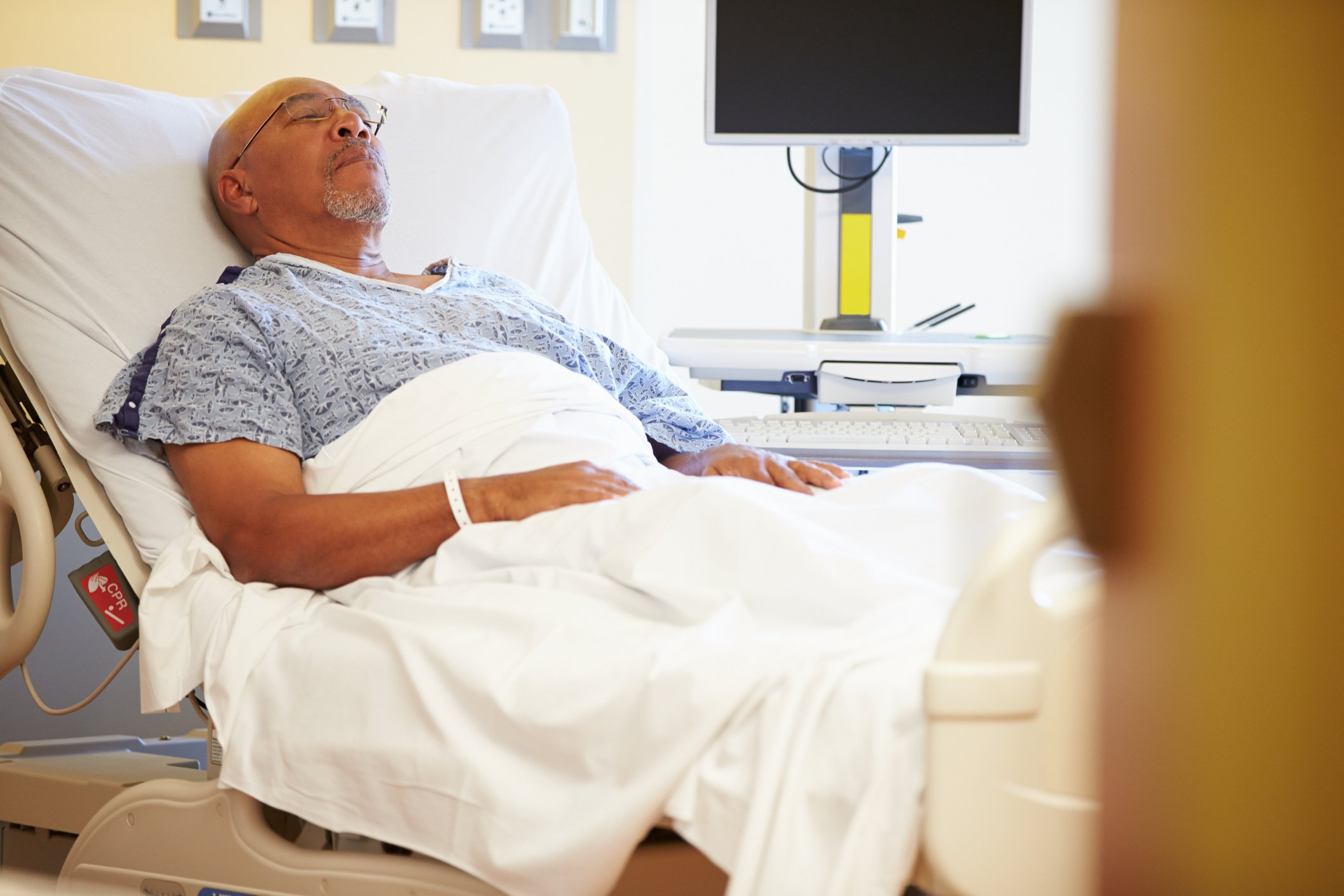 Senior man in sleeping in a semi-reclined hospital bed