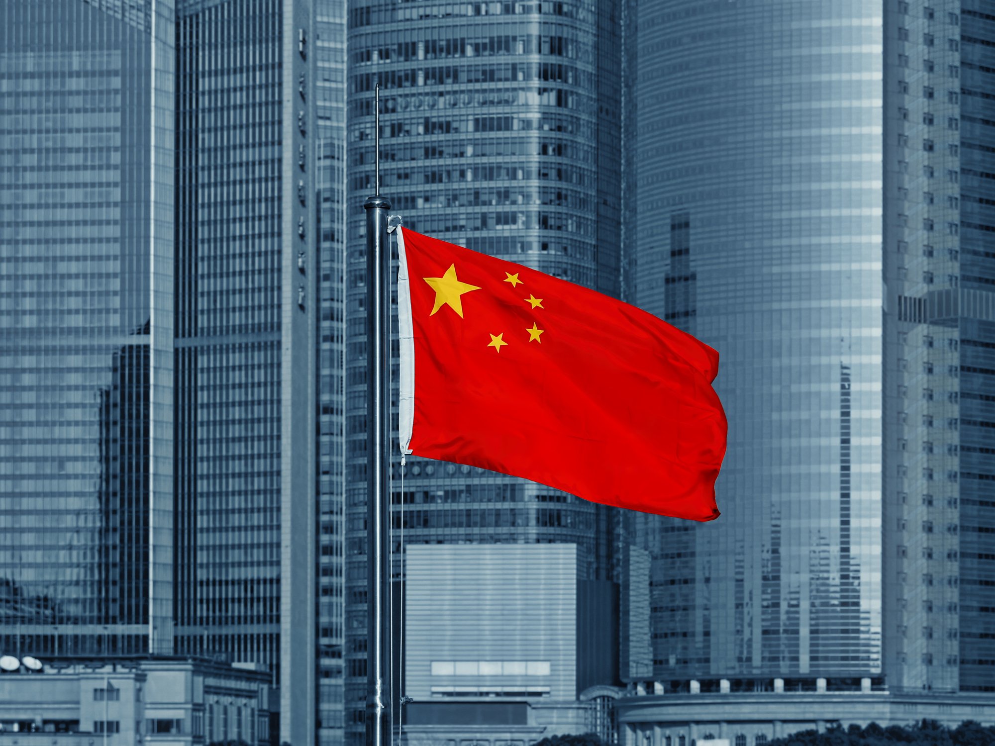 A Chinese flag with skyscrapers in the background.