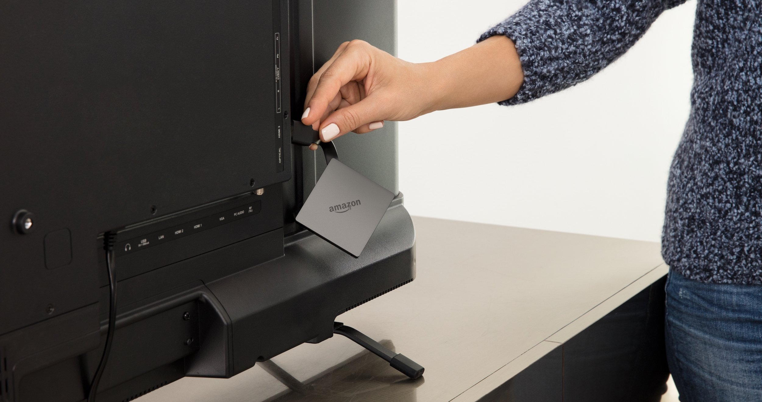 Person plugging in Fire TV dongle into back of TV
