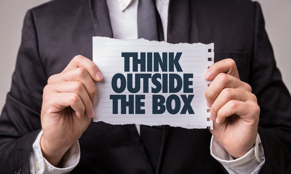 A man holds a paper that says think outside the box.