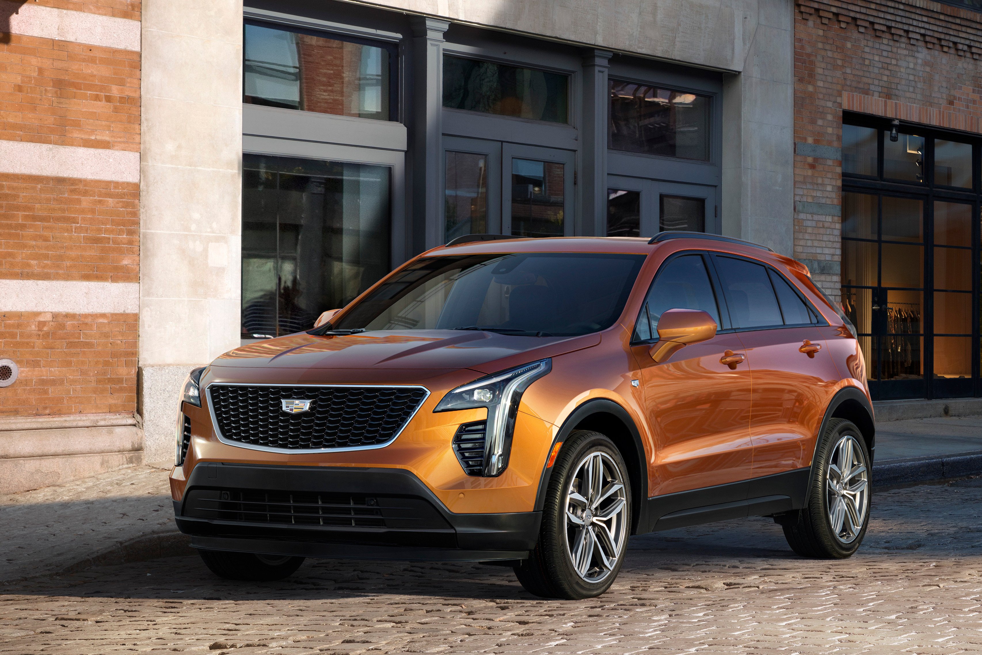 A copper-colored 2019 Cadillac XT4, a compact crossover SUV, parked in front of a commercial building. 
