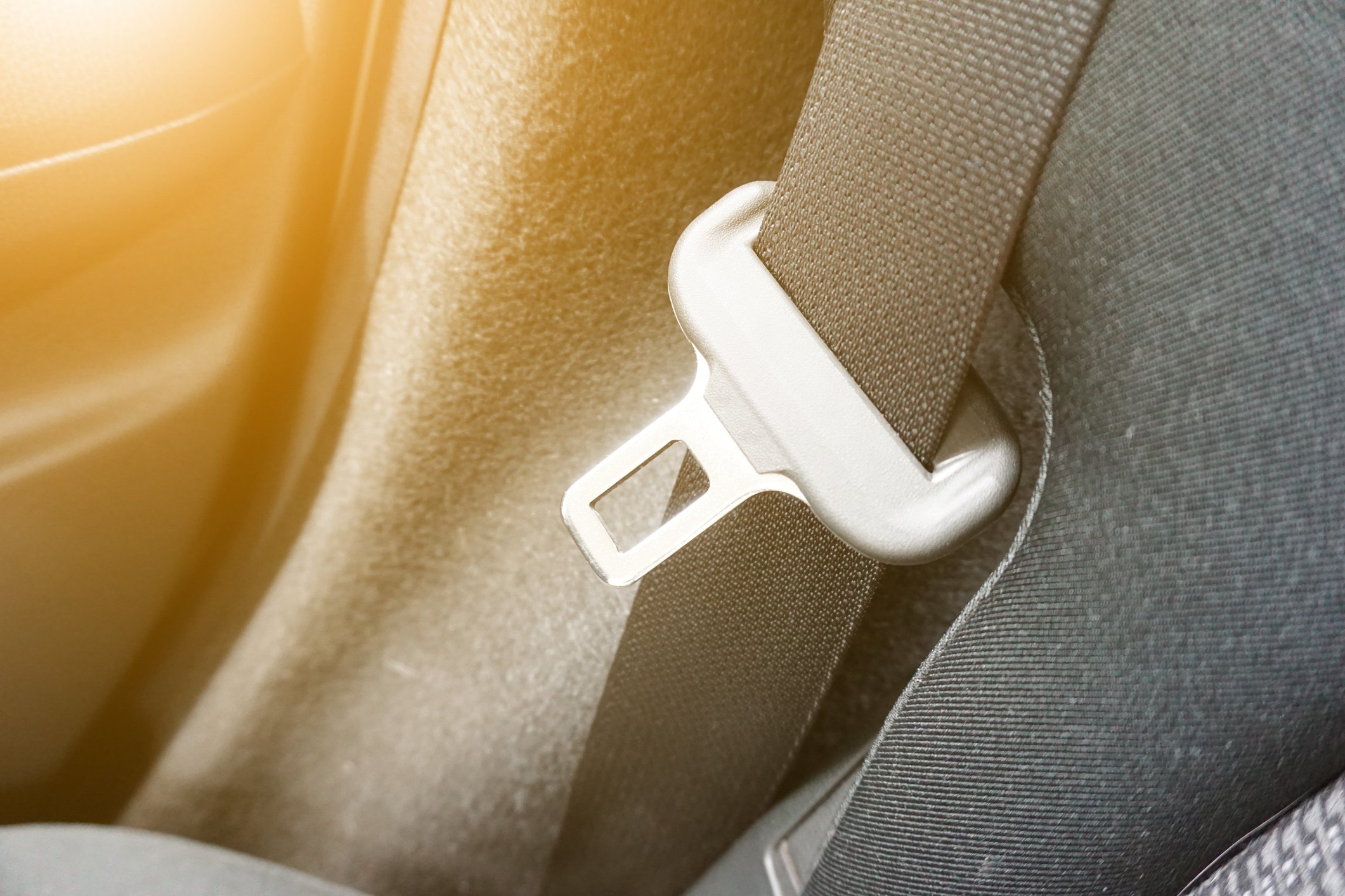 A seat belt in a car with the sun shining in.