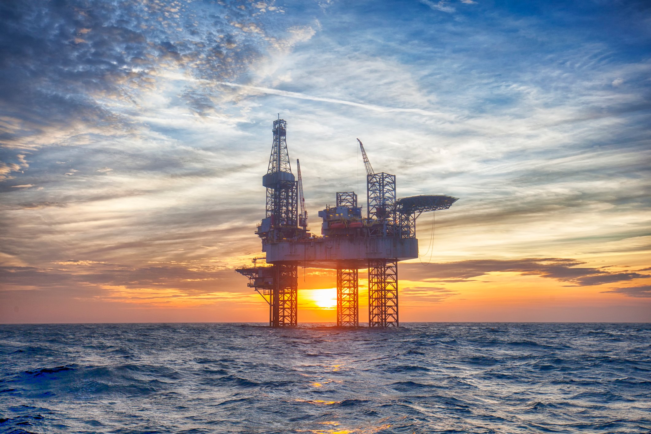 An offshore drilling rig at sunset.