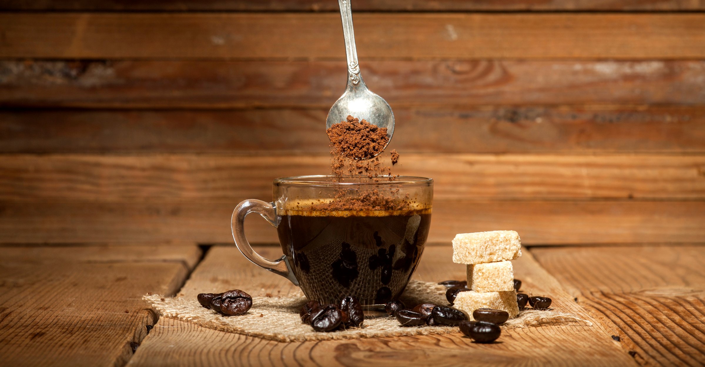 cup of instant expresso on table with spoon above. 