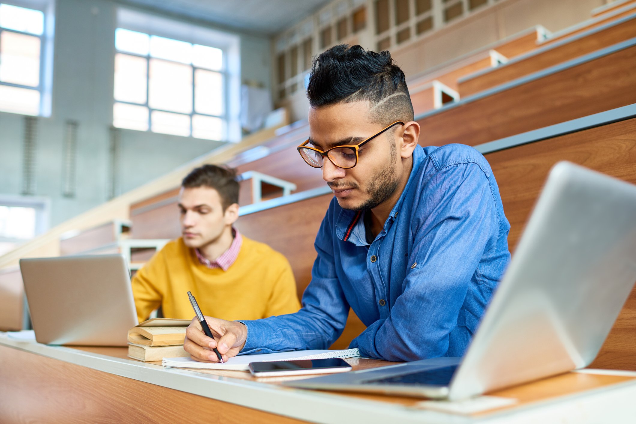 Two students in a study hall, working on their computers