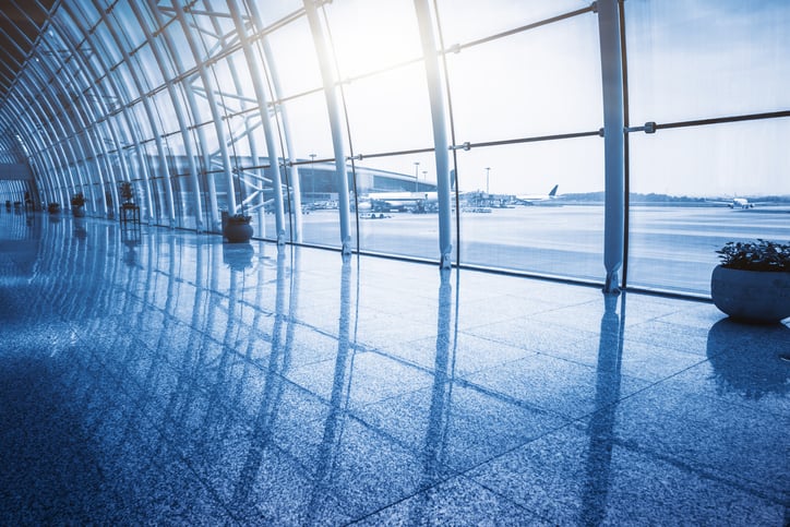 Tall arched windows at airport terminal overlooking planes.
