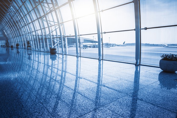 Tall arched windows at airport terminal overlooking planes.
