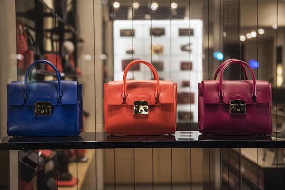 Blue, orange, and purple handbags on display.
