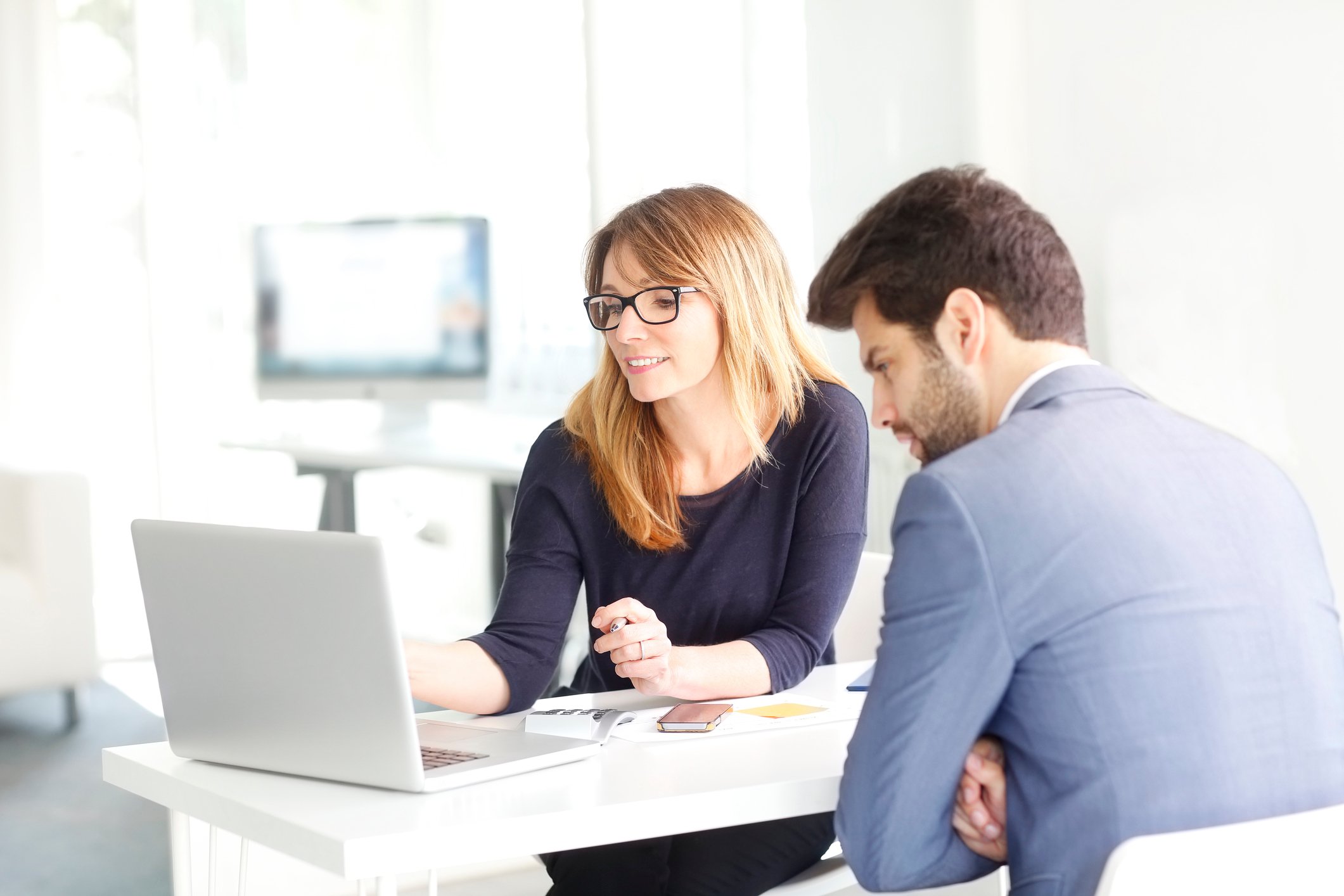 Woman showing a man something on her laptop screen