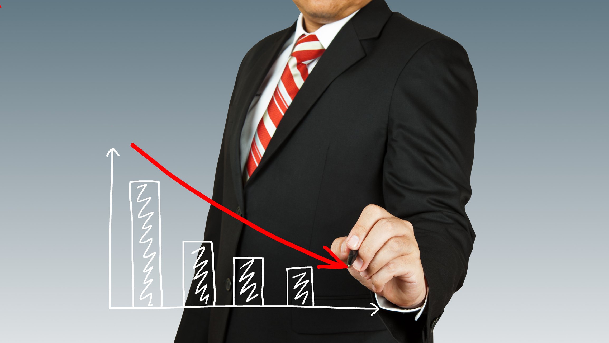 Businessman drawing red line pointing downward on top of down-trending bar chart