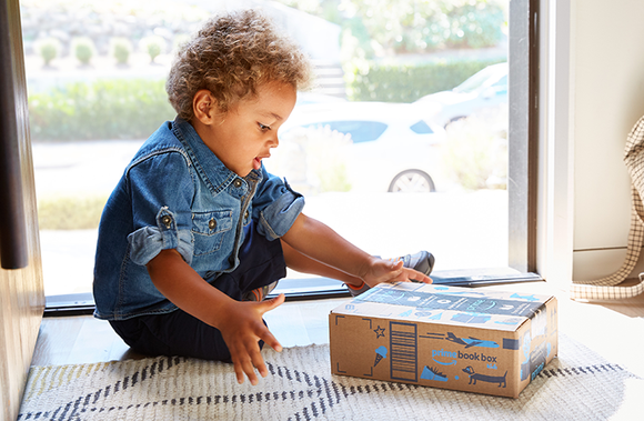A child looks at an Amazon delivery box.