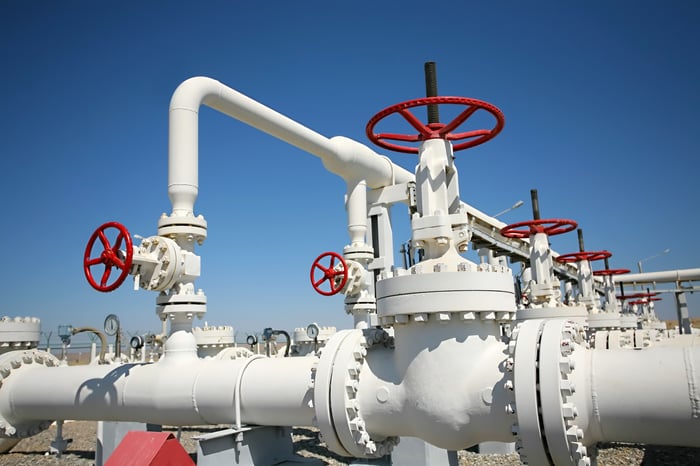 I set of white oil pipelines connecting with red knobs to operate valves.