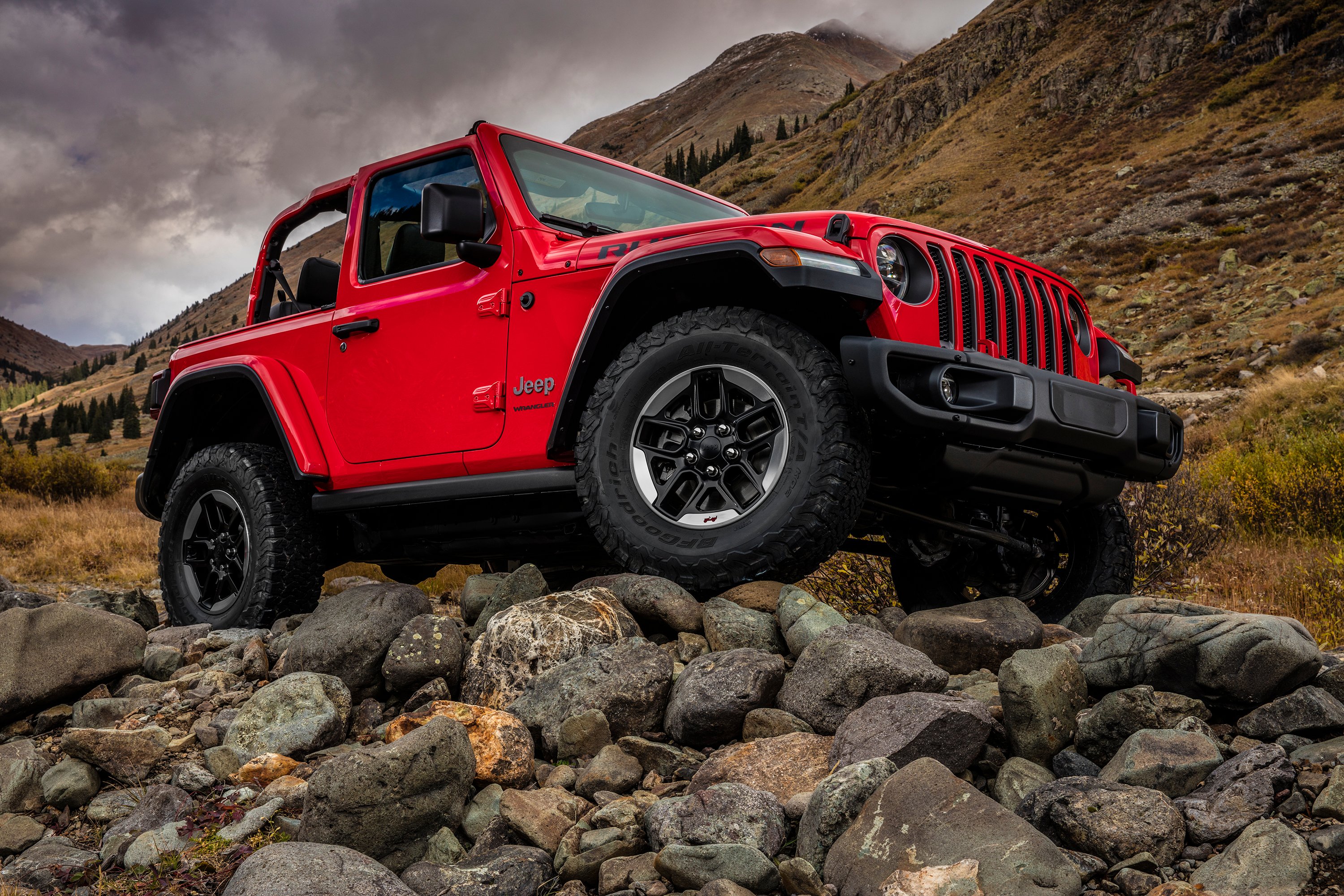 A red 2018 Jeep Wrangler SUV is shown atop a very rocky hill. 