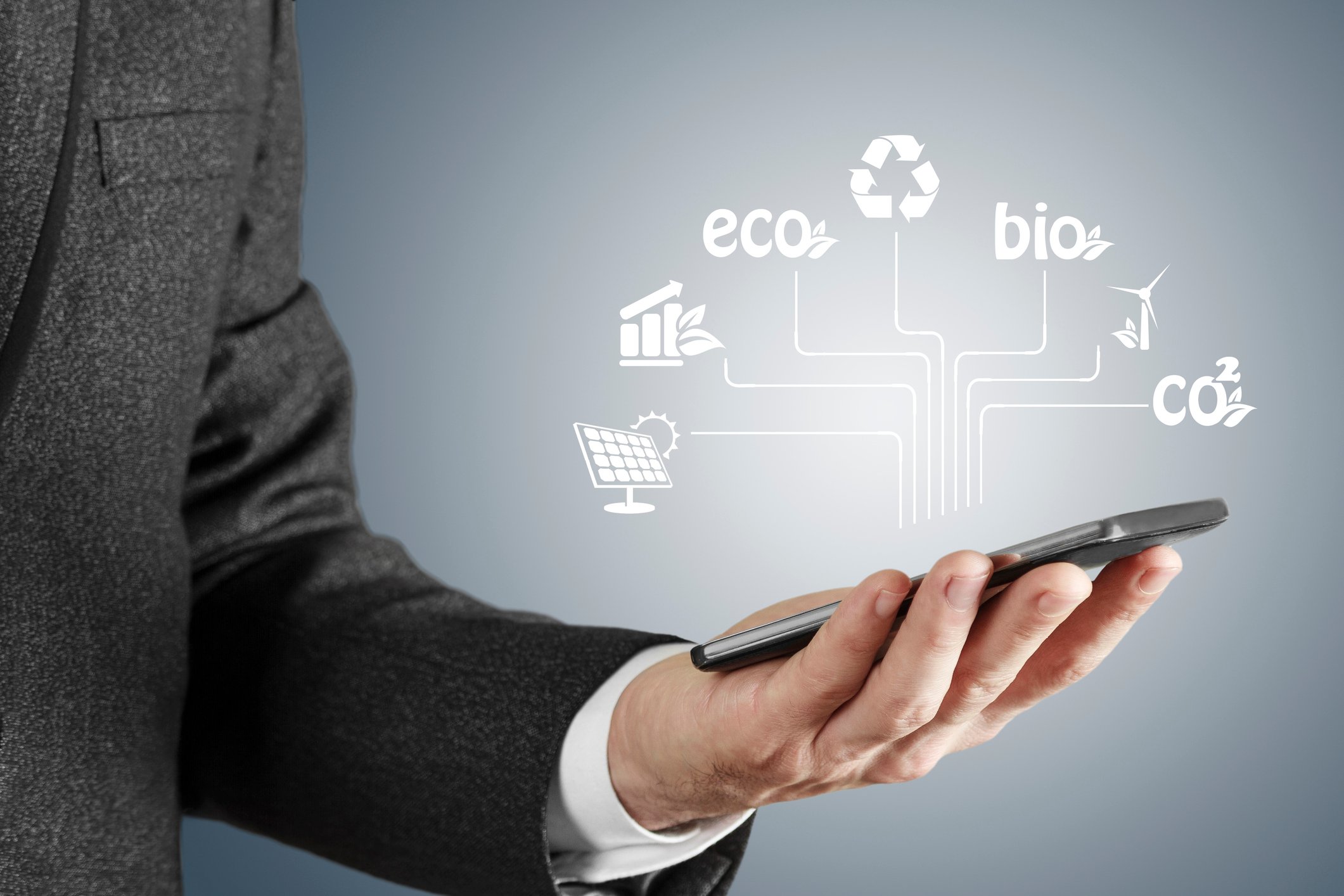 A man holding out his smartphone with various icons about renewable energy floating over it.