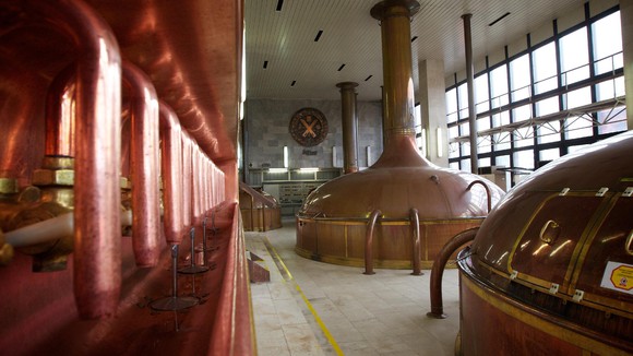 Large brewing vats and equipment in an old-style factory setting.