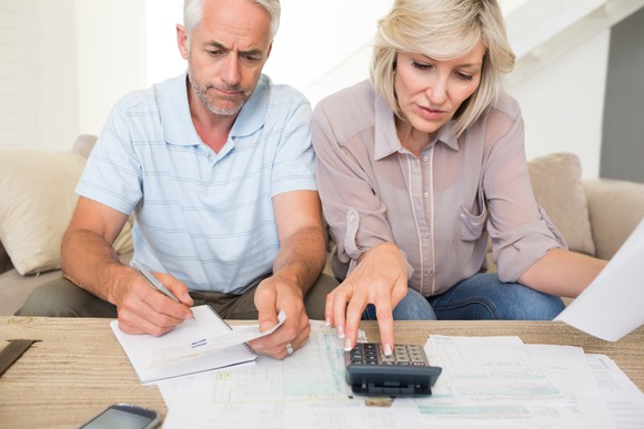 Older couple with calculator and financial paperwork.