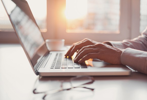 Man using a laptop with glasses placed on the table