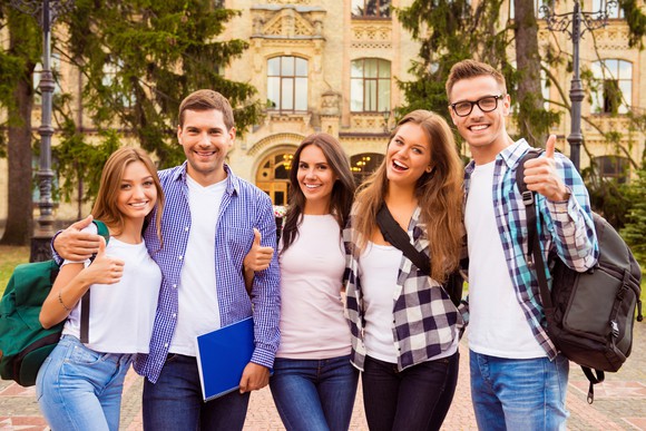 Five students posing for a picture on a college campus.