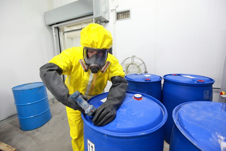 A person fastening a barrel containing chemical wastes.