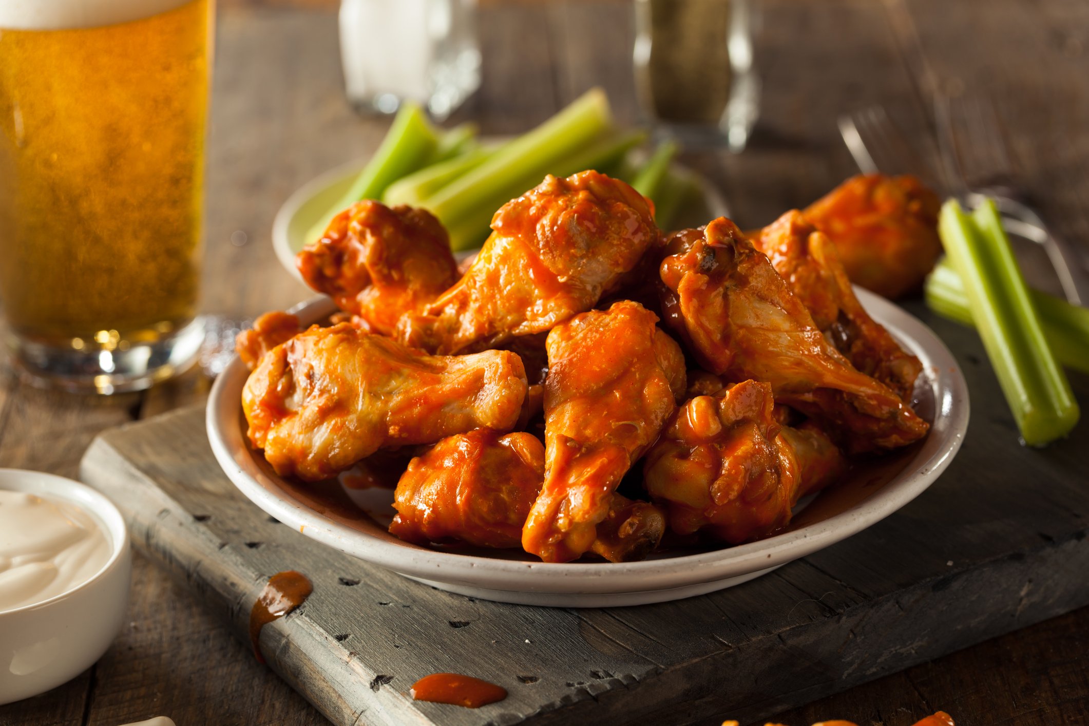 Plate of buffalo chicken wings with beer in the background