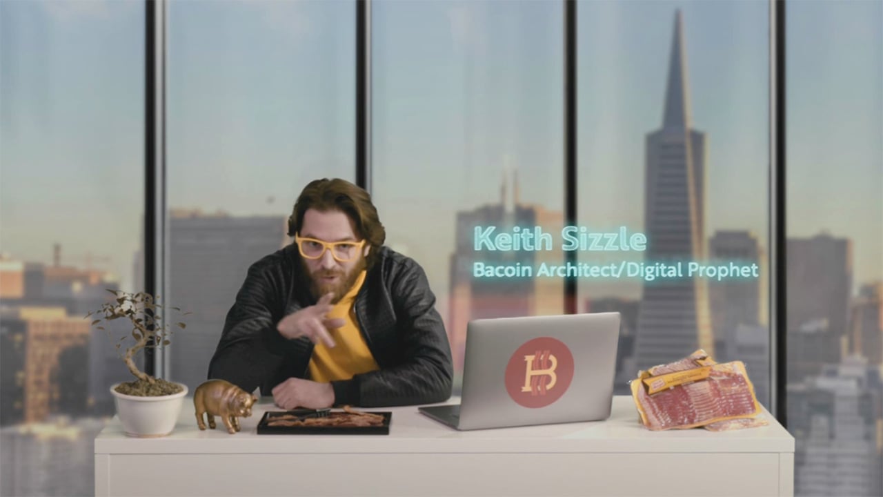 a man sits at a desk with Oscar Meyer meats and a laptop and funny glasses. 