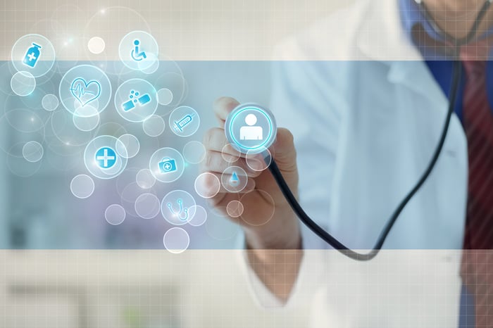 Doctor pressing stethoscope up to various medical symbols