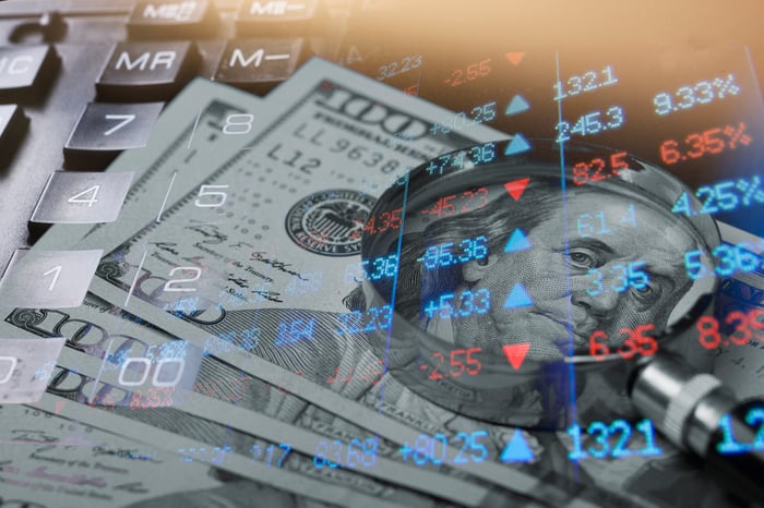 $100 bills superimposed over stock index board.