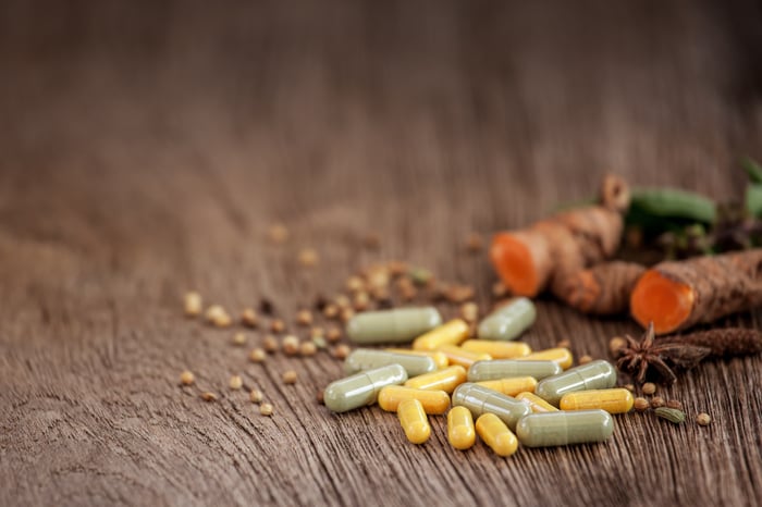 Supplements on a table next to seeds and root vegetables.