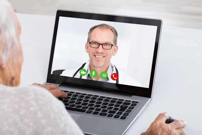 A doctor speaking to a patient using a laptop computer.