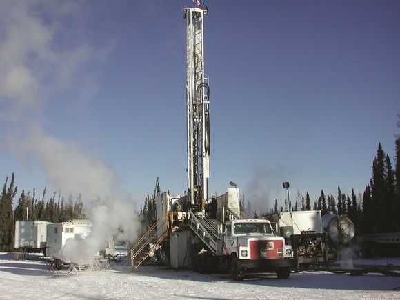 Land-based oil drilling rig in winter conditions in a pine forest.