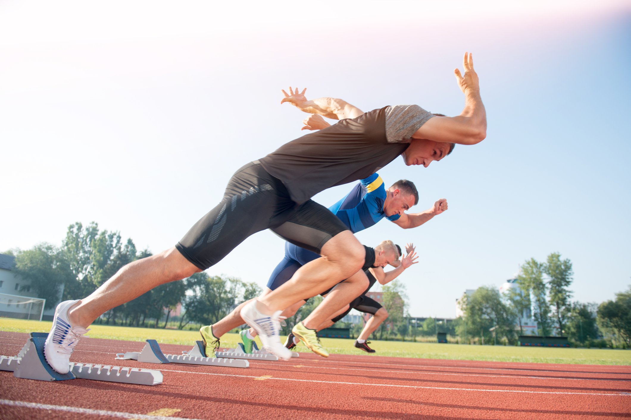 Three runners starting a sprint race.