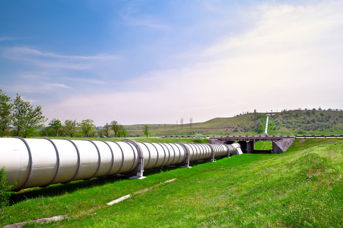 A pipeline on green grass stretching over the horizon.