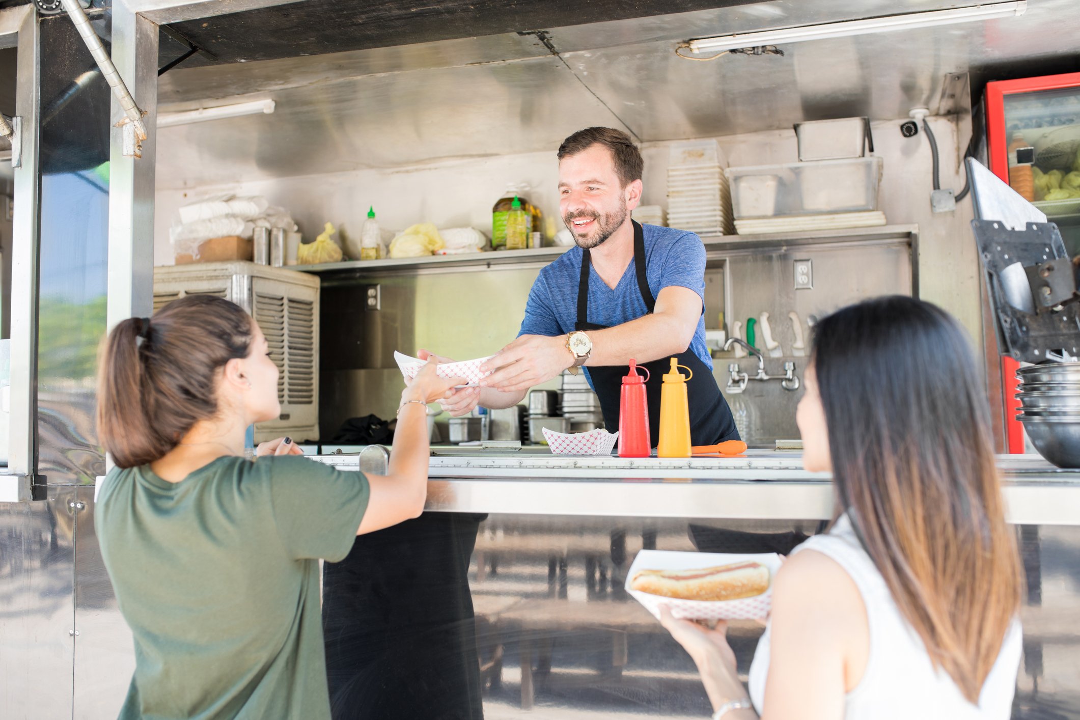 A man hands a woman food from a food truck.