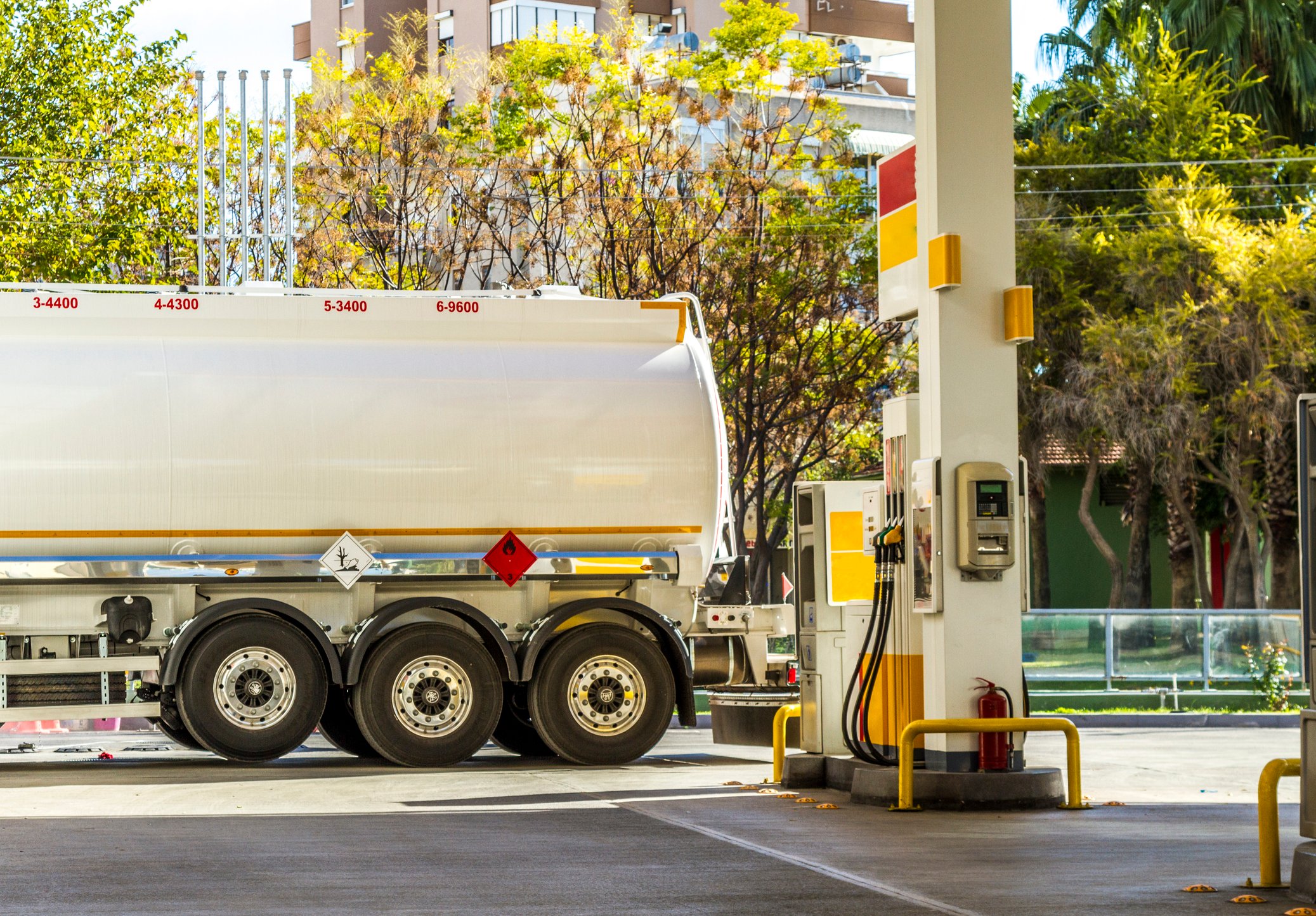 Natural gas tanker parked next to a fuel pump.