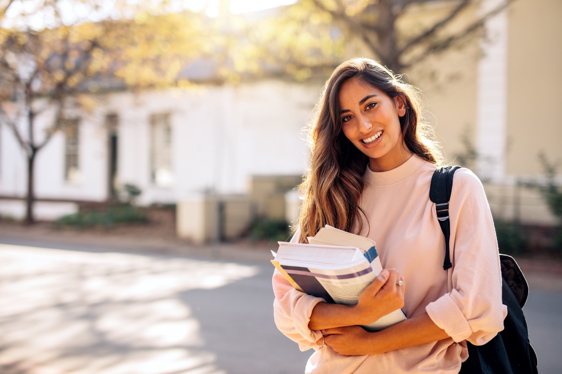 Young woman with backpack holding books