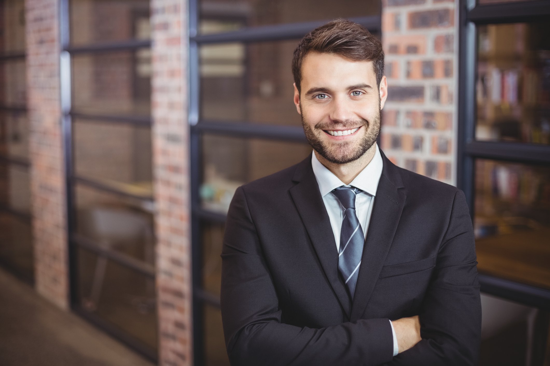 Man in suit with his arms folded smiling at the camera.
