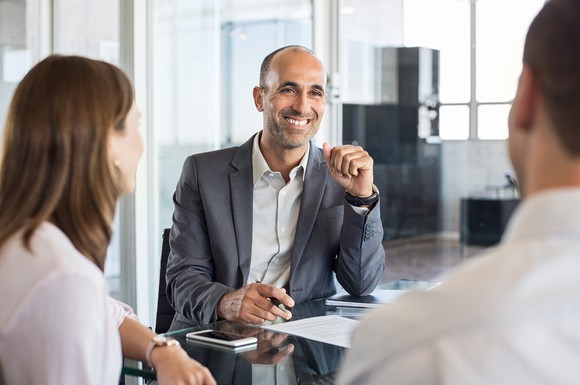 Man in suit sitting across from a professional female and male