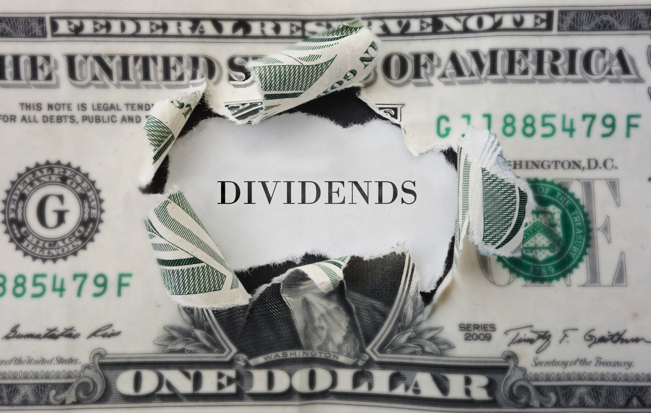 One dollar bill with center cut out, dividends written in its place.