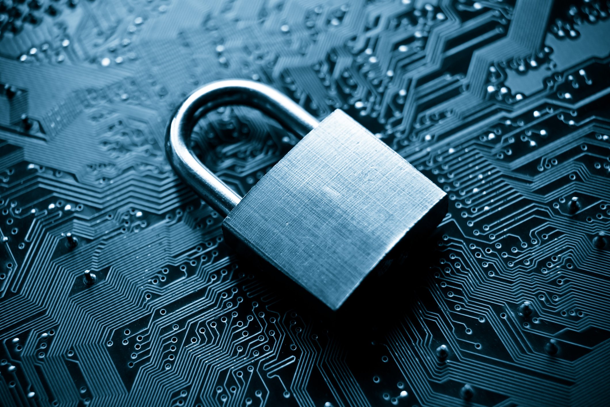 Metal padlock sitting on top of a circuit board. Cybersecurity concept