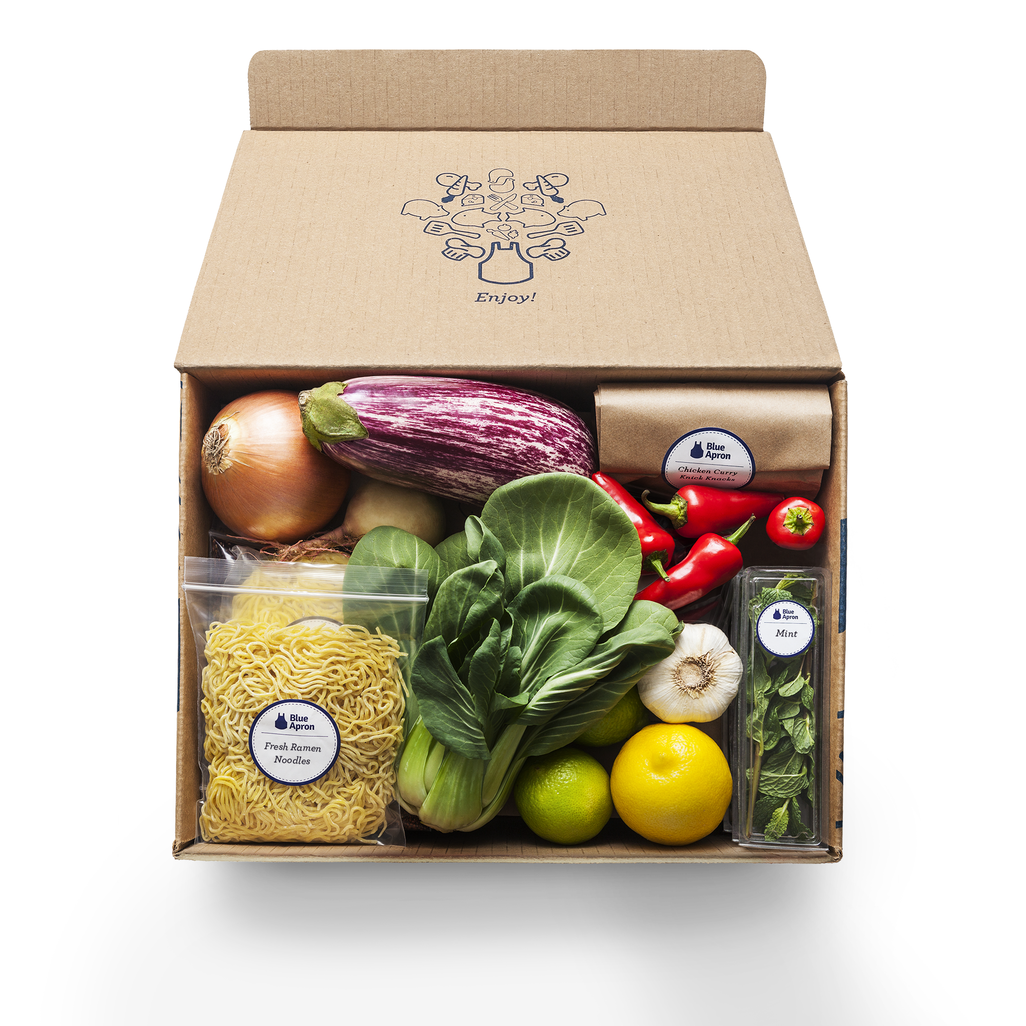 A Blue Apron box with various fresh ingredients like lettuce, red peppers, and onions
