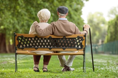 older couple retired sit on park bench
