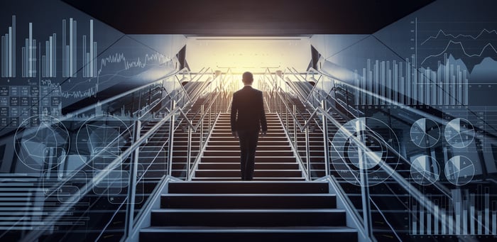 Man climbing stairs surrounded by stock graphs.