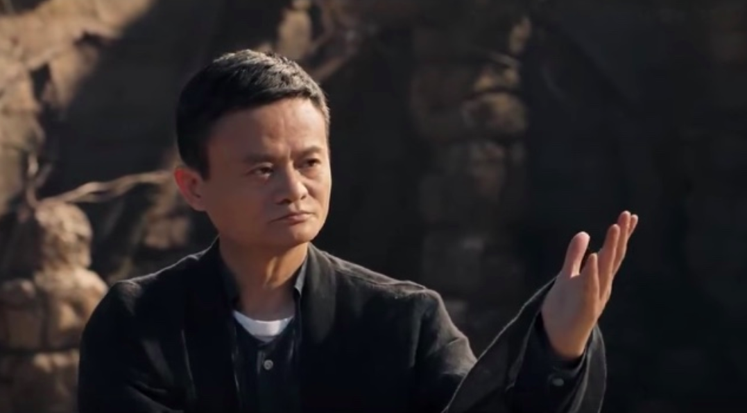 Alibaba founder Jack Ma looks pensive while raising his left hand.