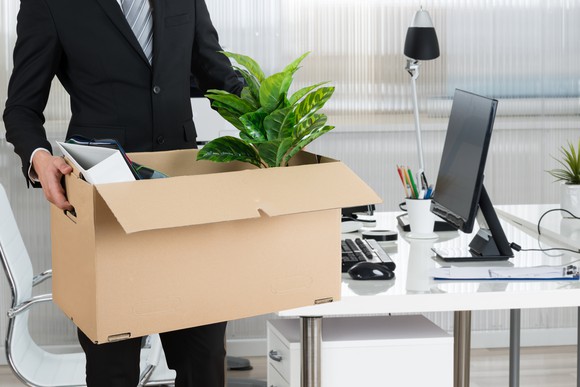 A man leaves his office with a box full of belongings.