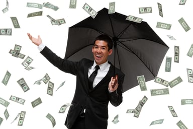 Money raining down on business man with umbrella