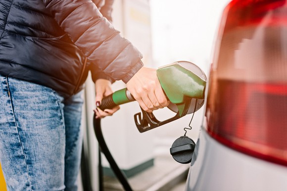 A woman pumping gas in her car.