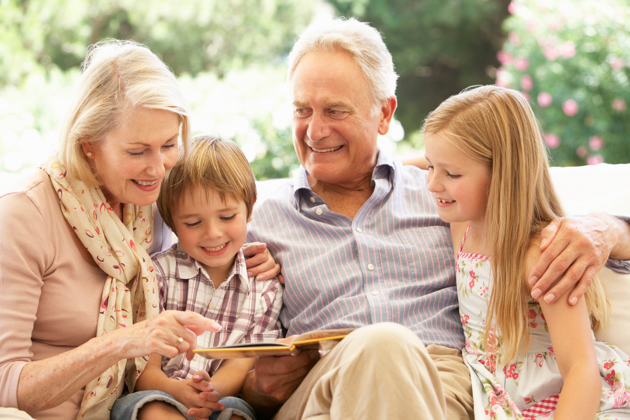 Grandparents reading to two young grandchildren.