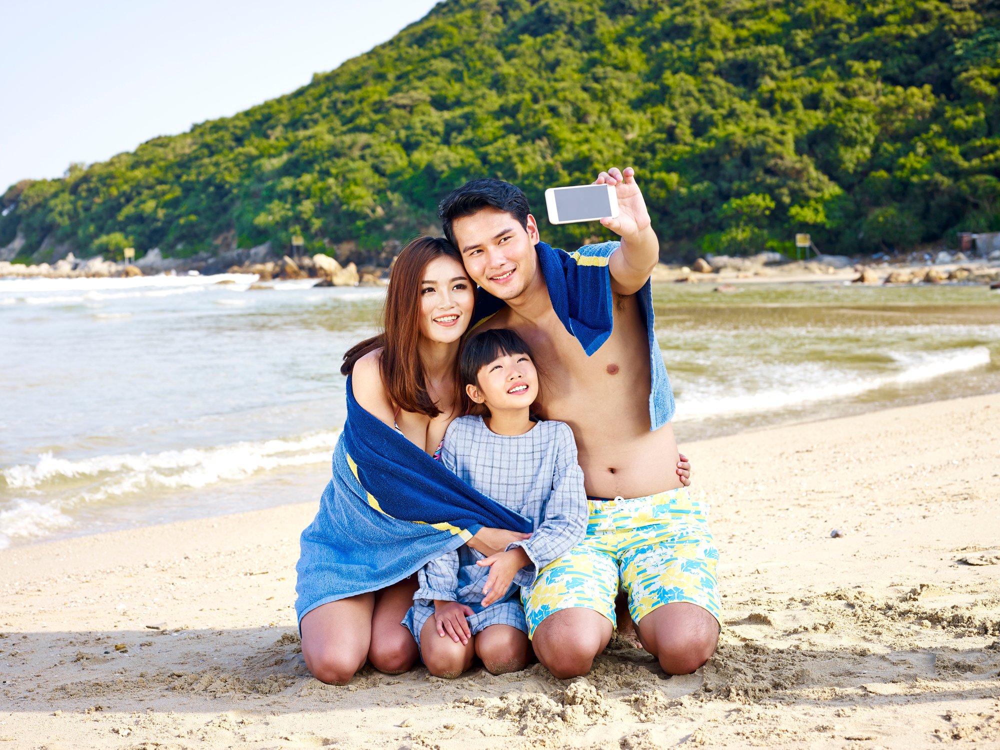 Man, woman, and child taking a selfie together on beach