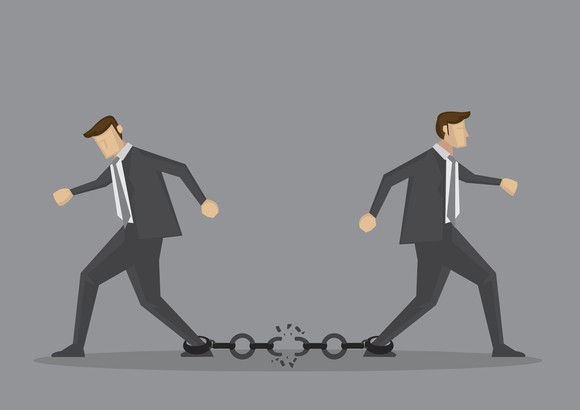 Two cartoon-style businessmen trying to walk away from each other, snapping a chain attached to their ankles.