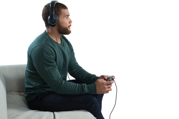 Adult male holding a gaming console controller and wearing an audio headset.
